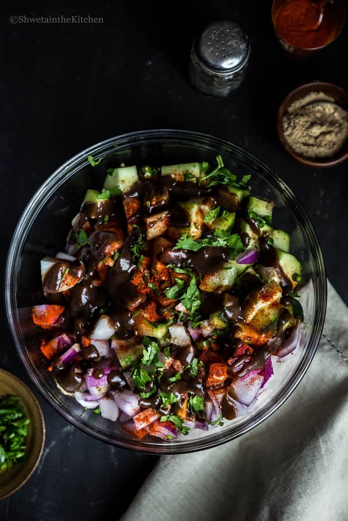 Bowl of red onion, cucumbers and arbi sprinkled with spices and drizzled with sweet chutney. 