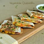 Vegetable quesadillas served on a wooden board with a guacamole dip
