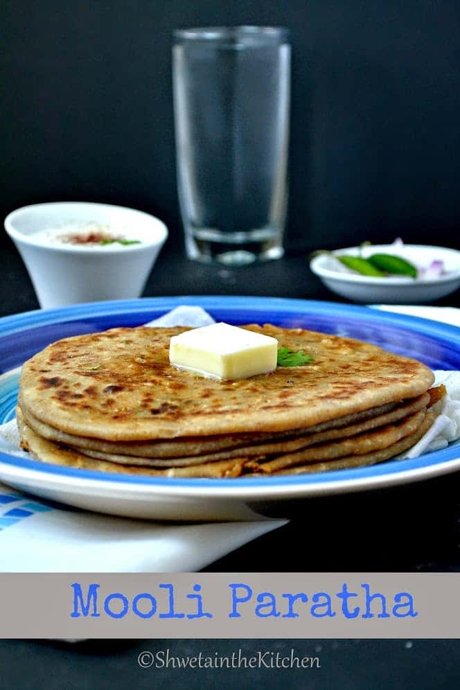 Close up of butter melting on top of mooli paratha on a blue plate.