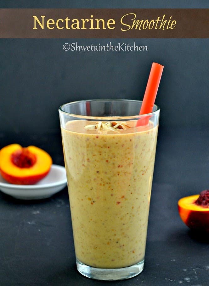 A red straw in a smoothie with nectarine halves next to it