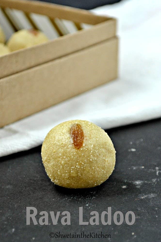 A rava ladoo with a raisin pressed into it on a work surface