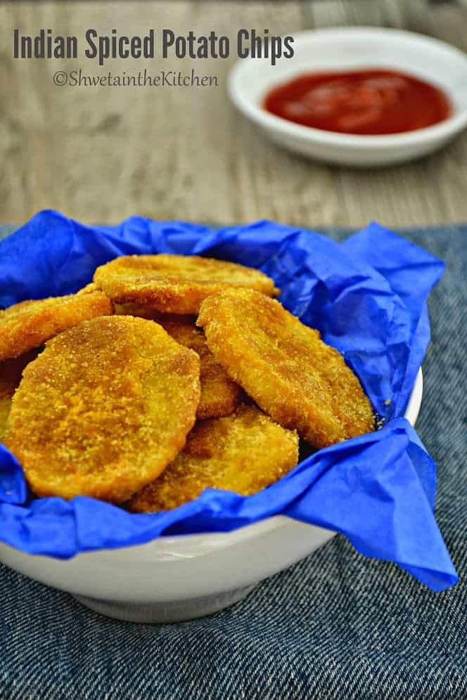 Indian spiced potato slices in a white bowl served with a tomato ketchup
