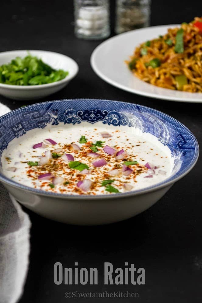 A bowl of yogurt dip served in front of a rice dish