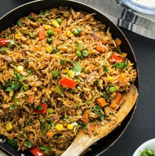Tawa pulao in a skillet with a wooden spatula
