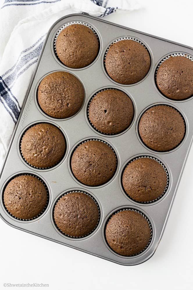 The baked chocolate cupcakes in a tin before being frosted