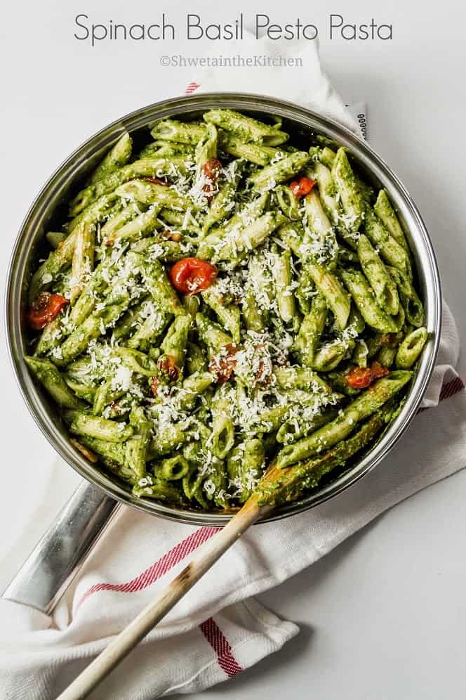 Spinach and basil pesto pasta in a pan with roasted tomatoes