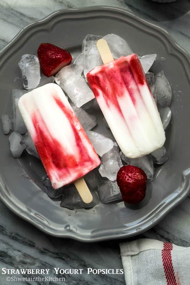 Two strawberry yogurt popsicles and a grey plate