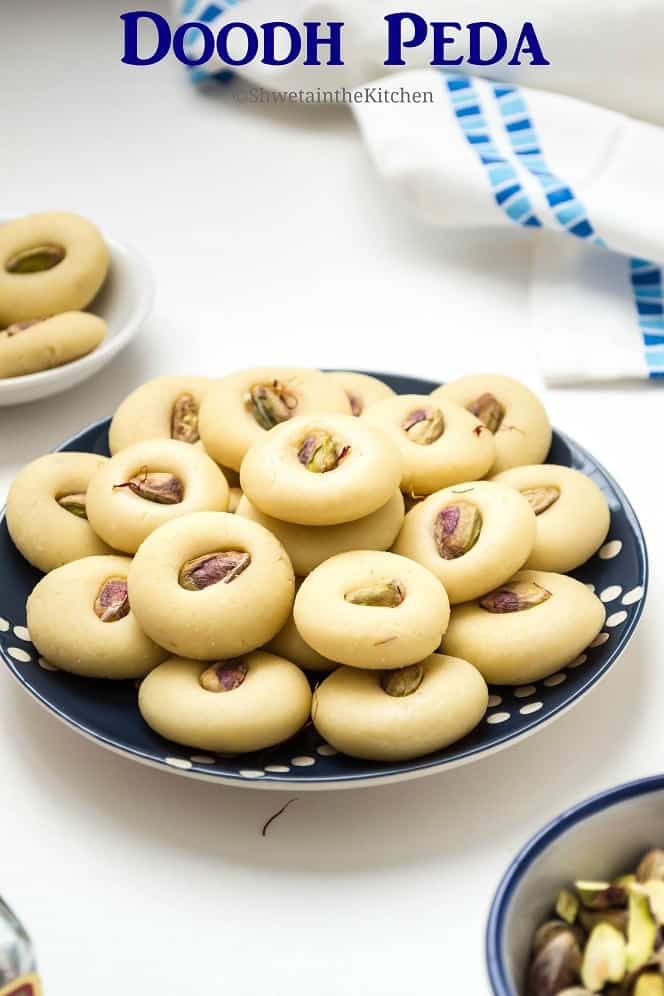 Doodh peda served on a plate next to a bowl of pistachios