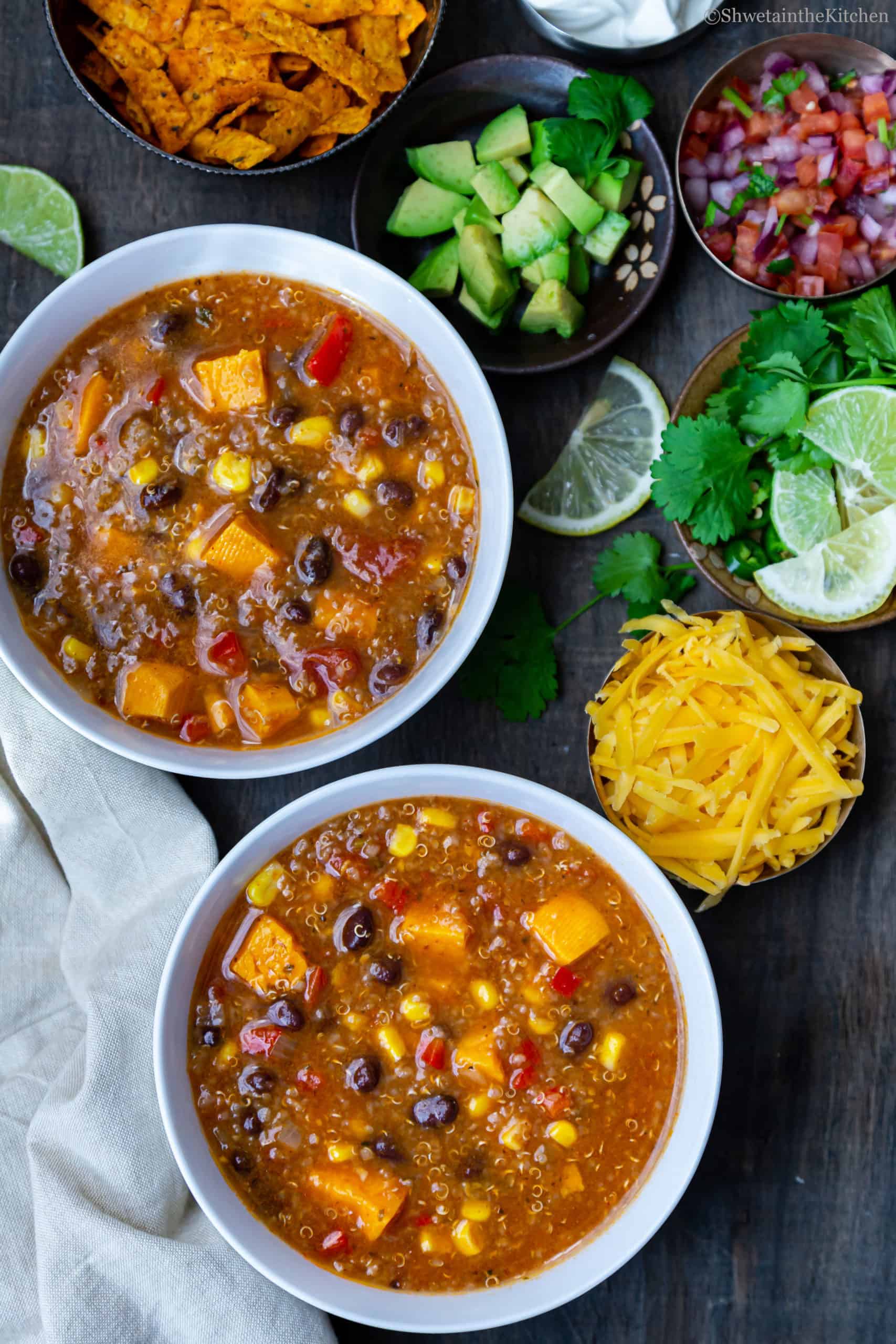 Quinoa Enchiladas Soup served in two bowls with toppings on the side. 