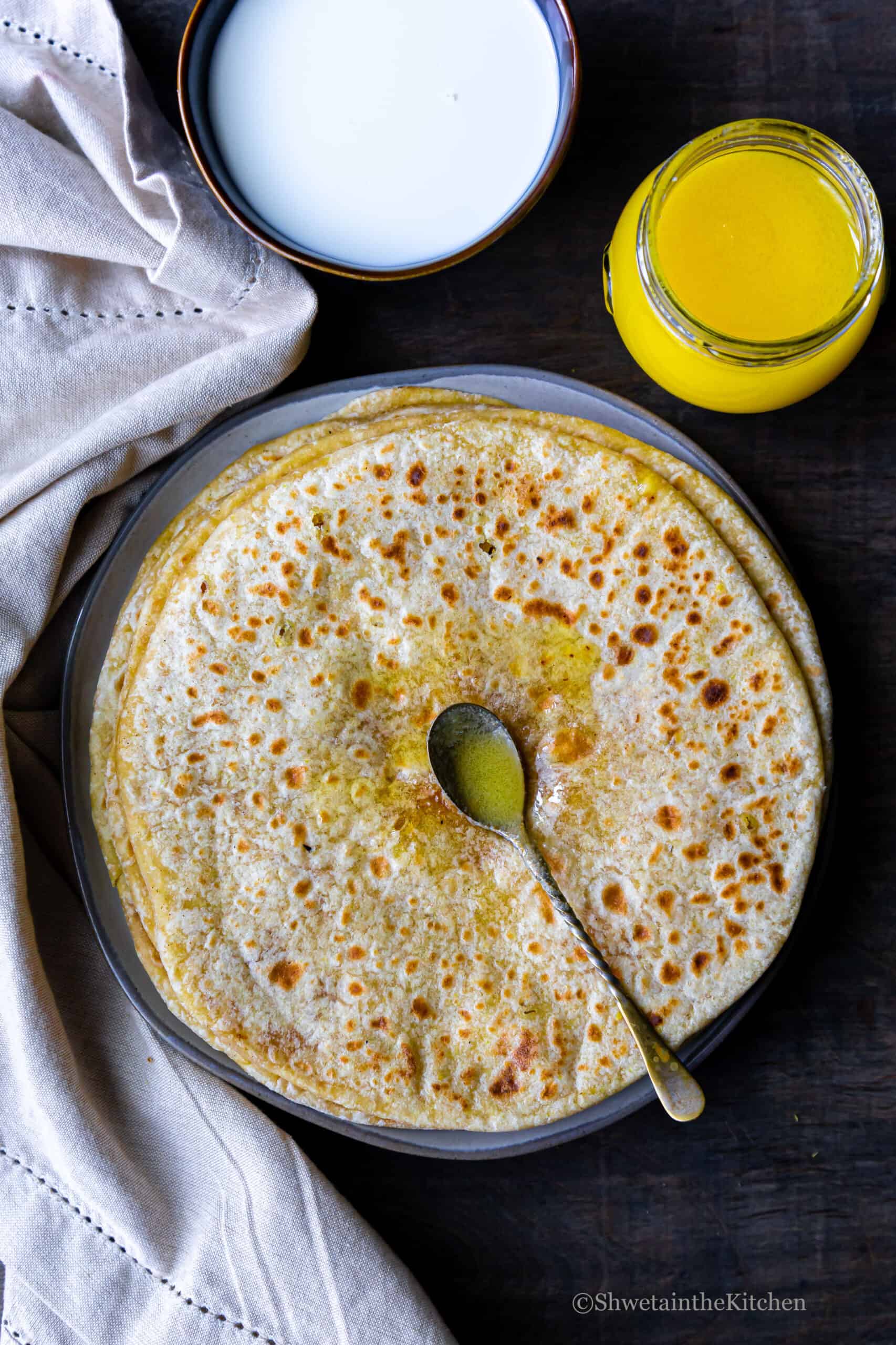 Top view of Puran Poli placed on a plate with ghee and milk on side