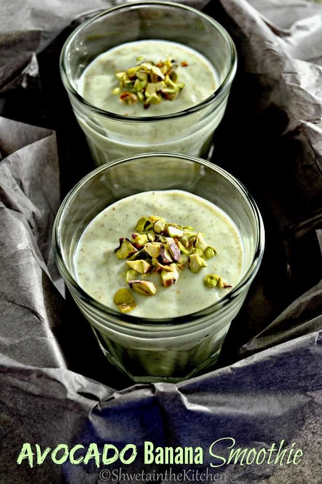 Two glasses of the avocado banana smoothie topped with pistachios