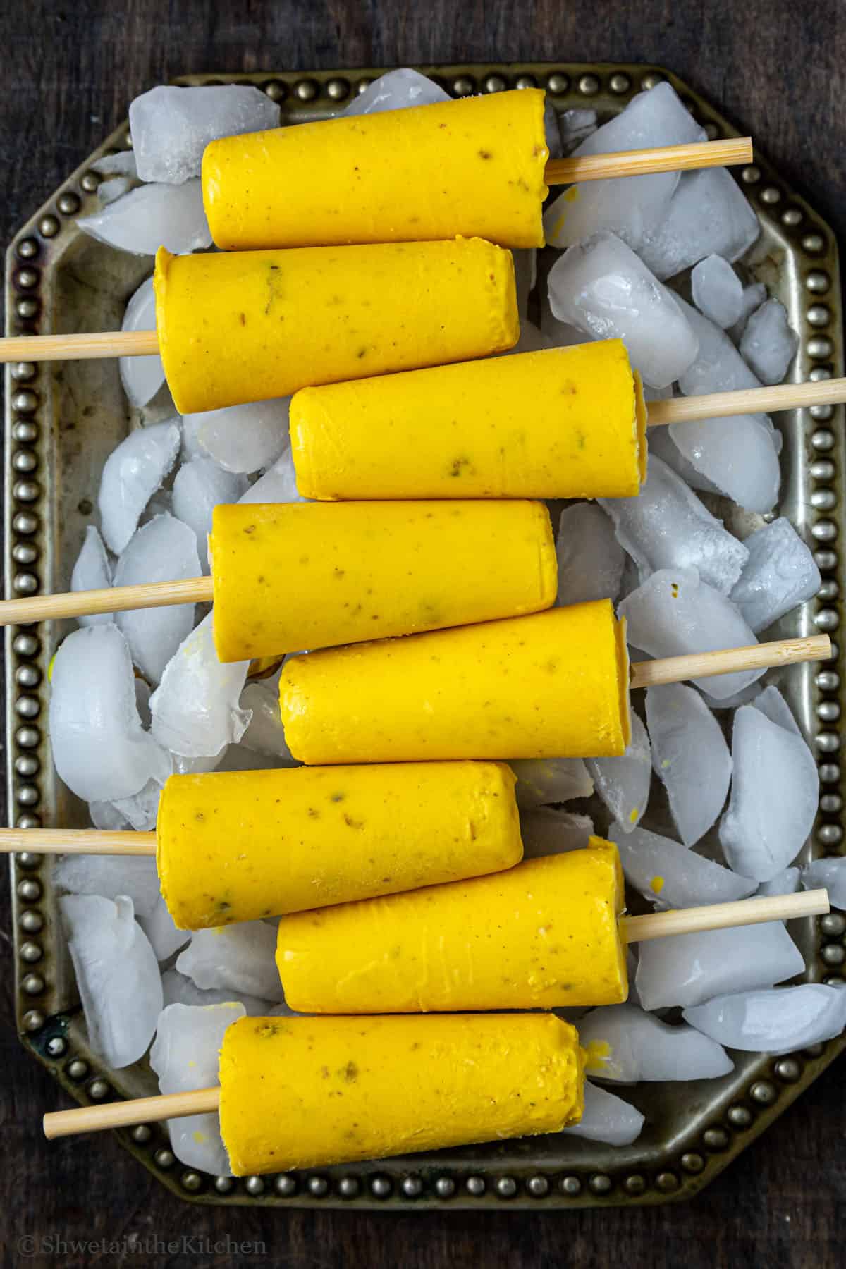 Top view of 8 Kulfi ice creams on an ice filled tray. 