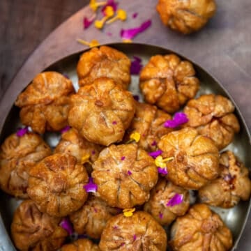 Fried Modak's arranged in tower on a plate, one placed on side with lamp light