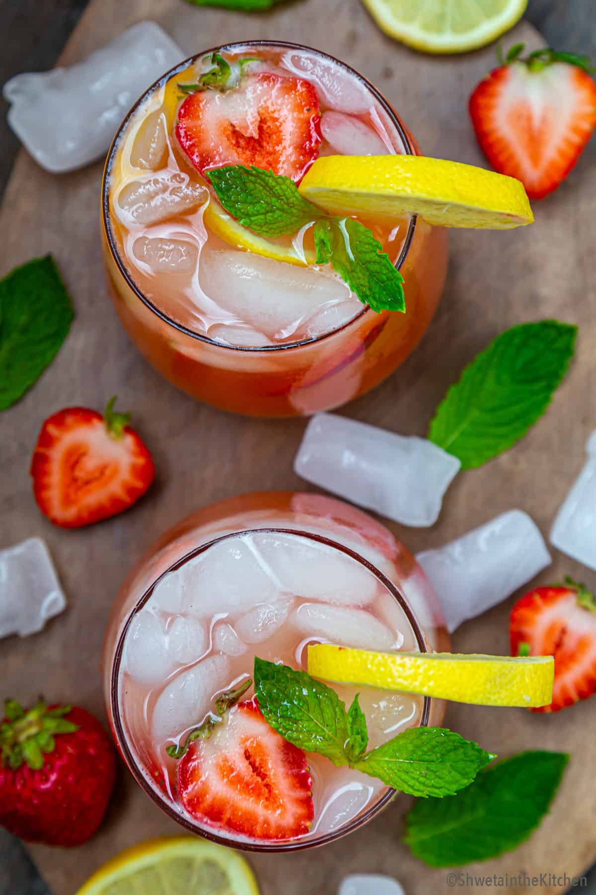 Top view of two strawberry lemonade glasses garnished with lemon slices, strawberry and mint