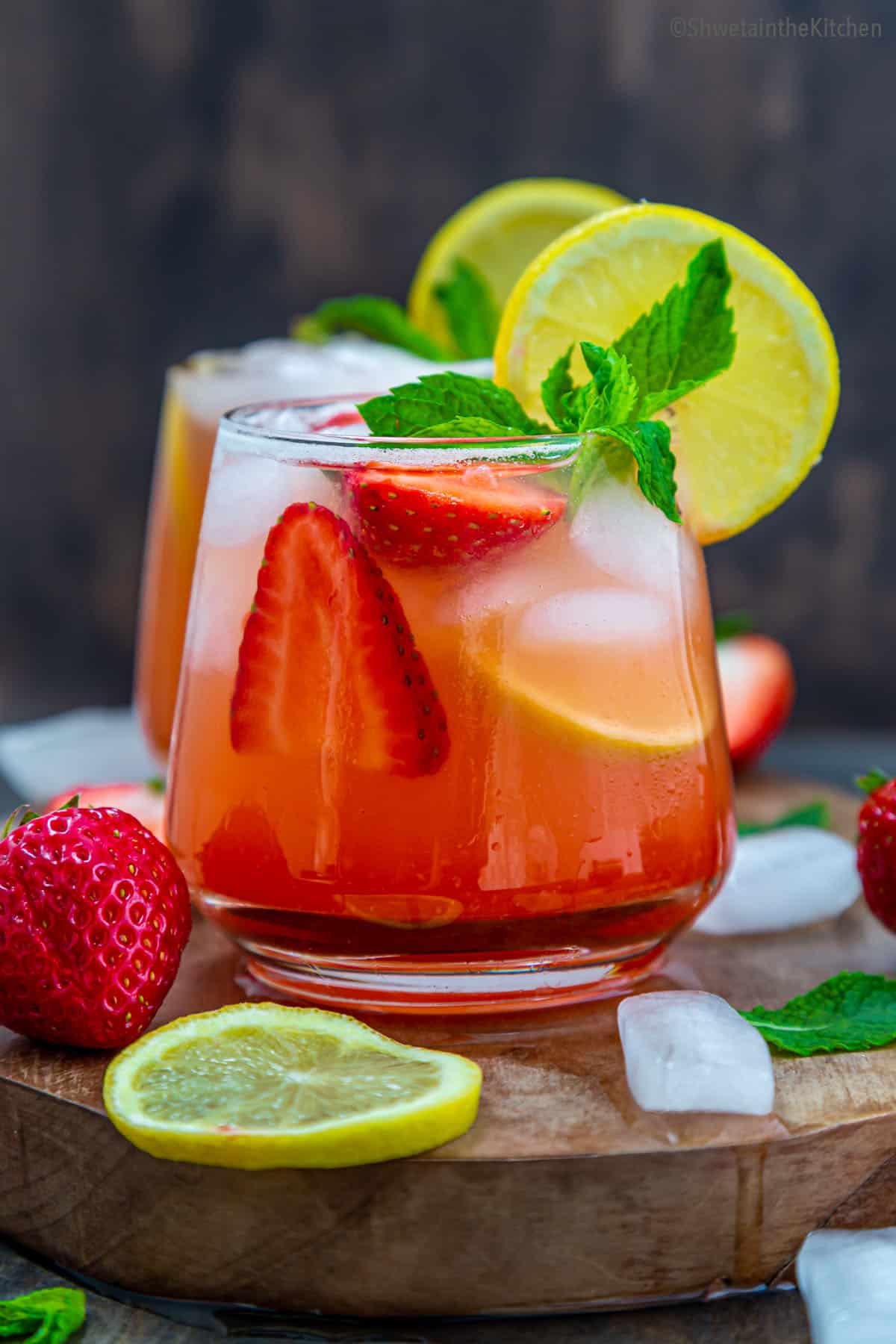 front view of chilled sparkling strawberry lemonade garnished with lemon slice and mint