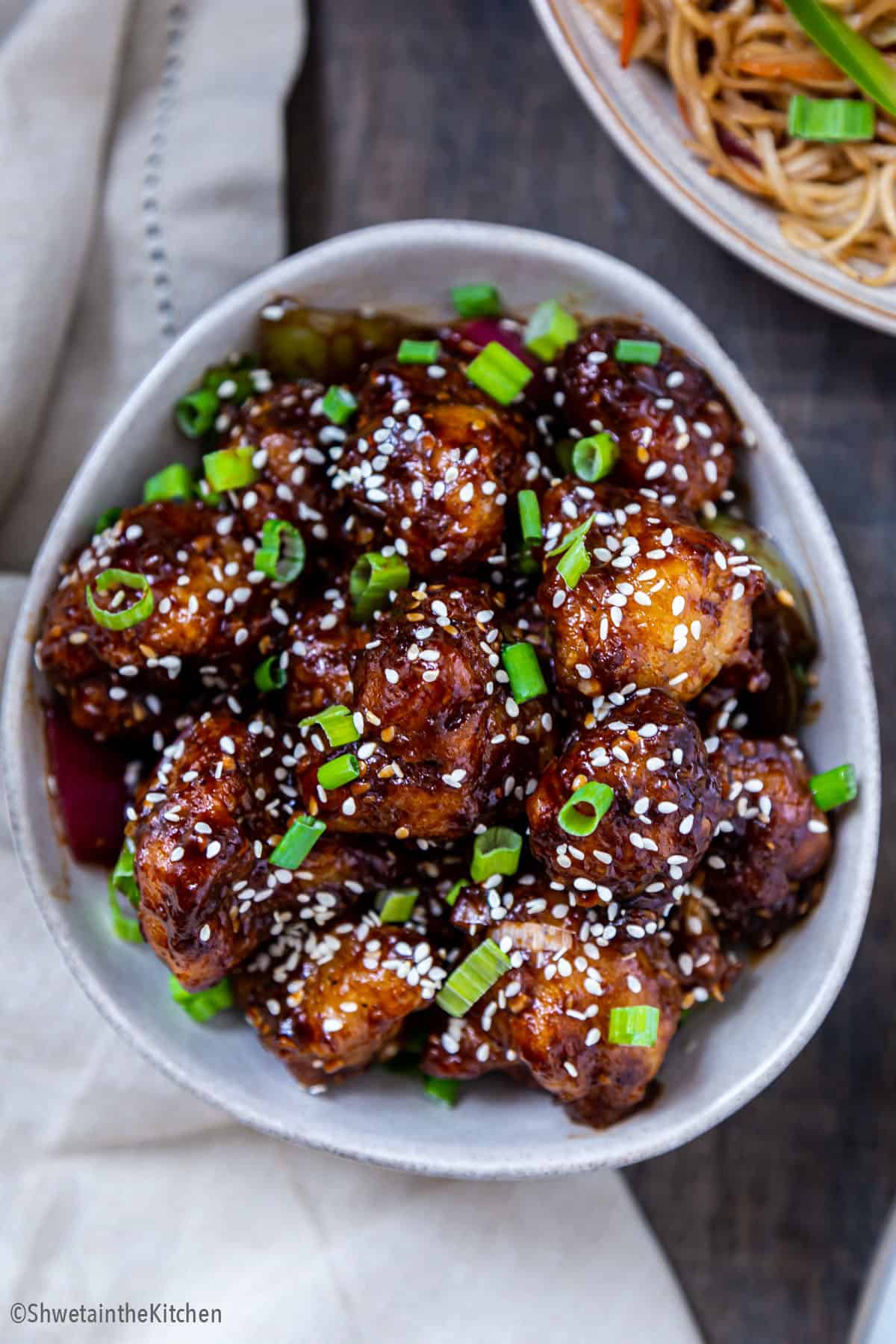 white bowl full of Gobi Manchurian garnished with spring onions green