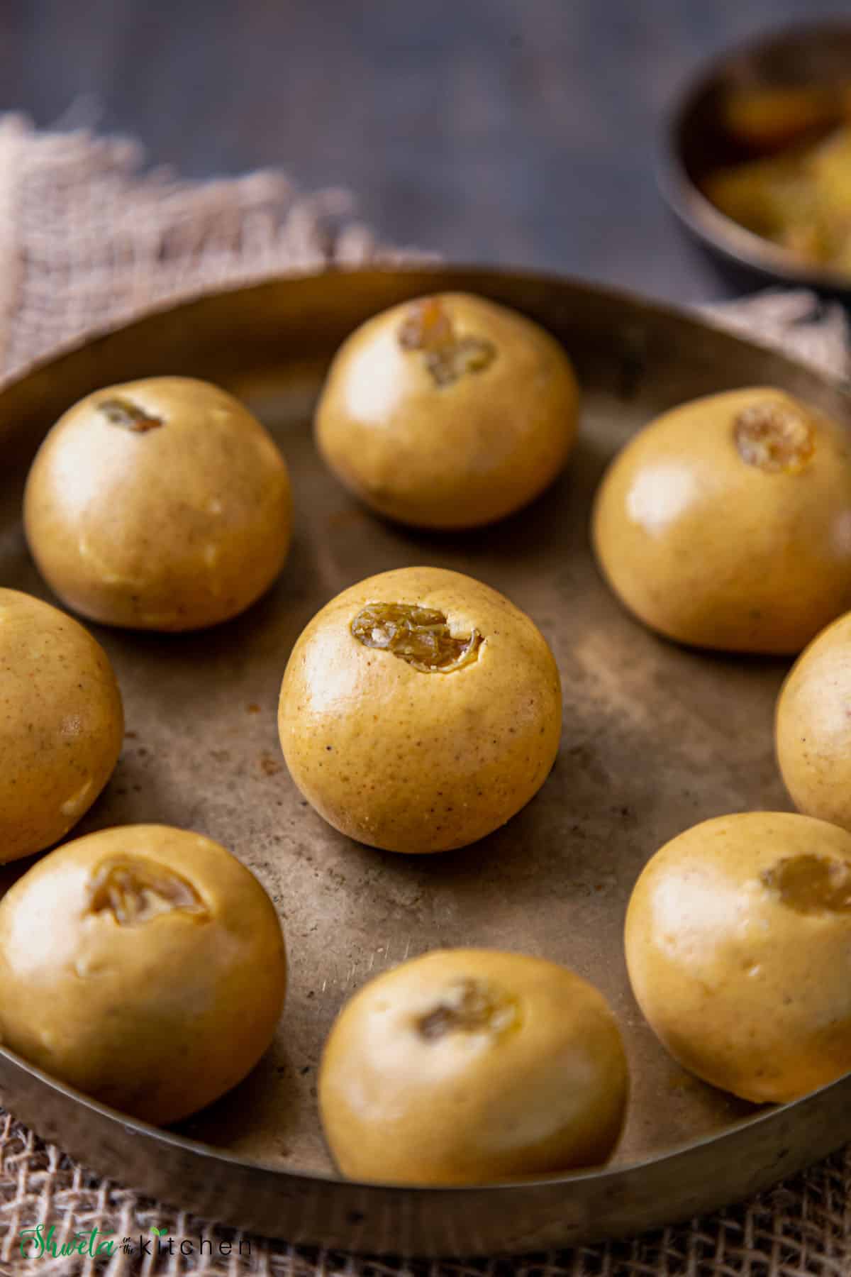 Besan laddu on a brass plate with focus on centre ladoo