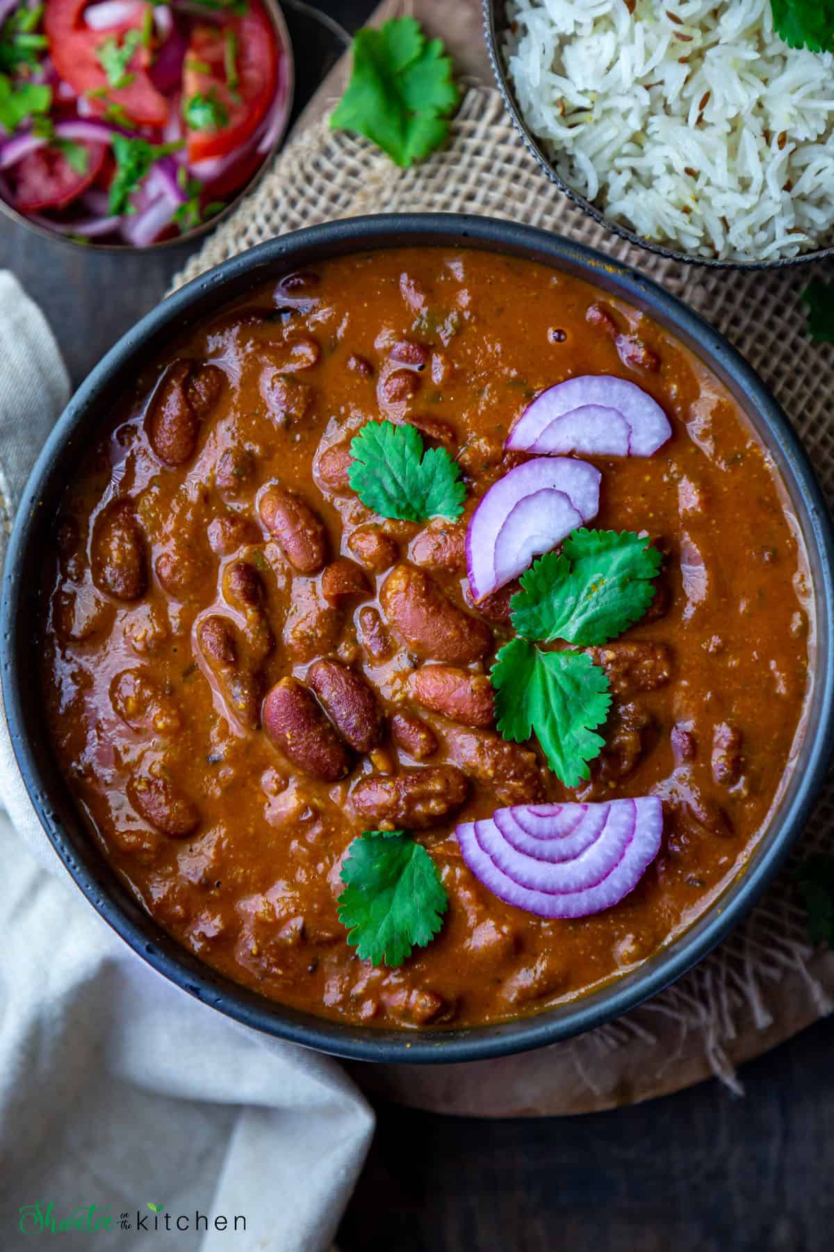 Bowl of Rajma garnished with cilantro and onions