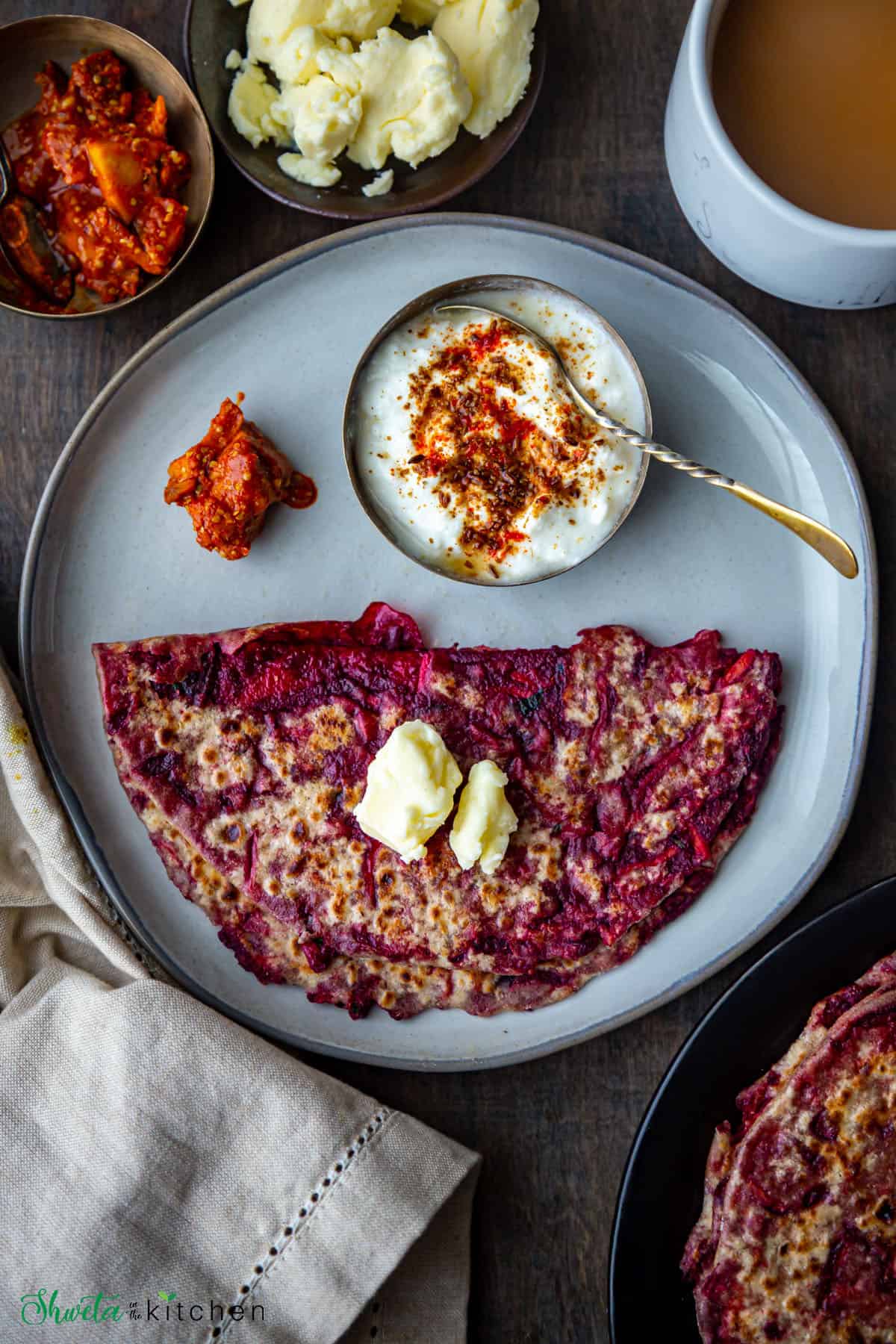 Aloo Beetroot Paratha on a plate with pickle and spiced yogurt