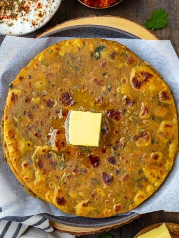 Dal Paratha with butter cube on top, pickle and yogurt on side