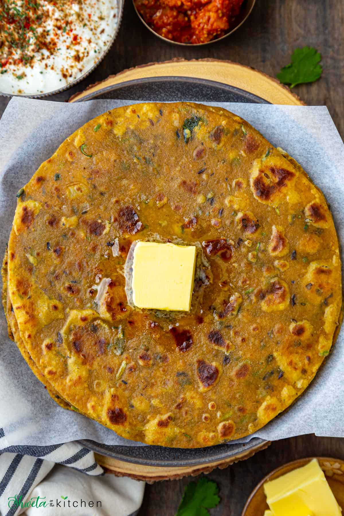 Dal Paratha with butter cube on top, pickle and yogurt on side