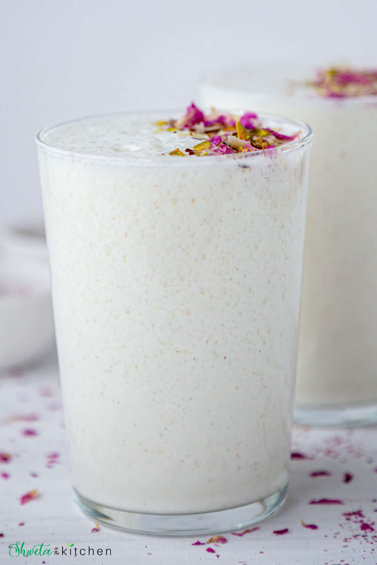 Front view of sweet lassi glass filled till rim and garnished.