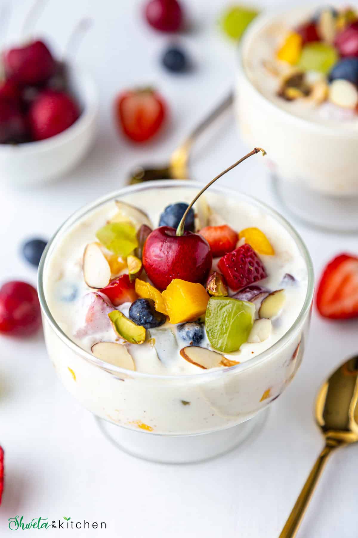 Close up of fruit salad with condensed milk bowl topped with more fruits and cherry 
