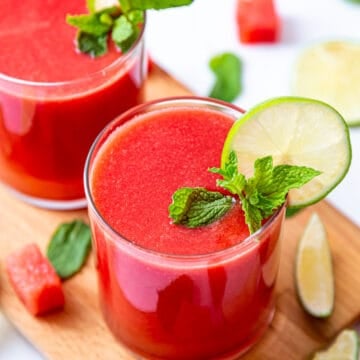 Two glasses of fresh watermelon juice garnished with lemon slice and mint leaves