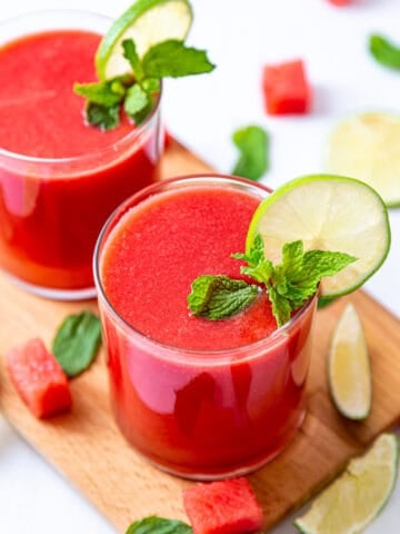 Two glasses of fresh watermelon juice garnished with lemon slice and mint leaves