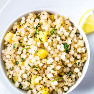 Sabudana Khichdi served in a white bowl on a plate with a slice of lemon
