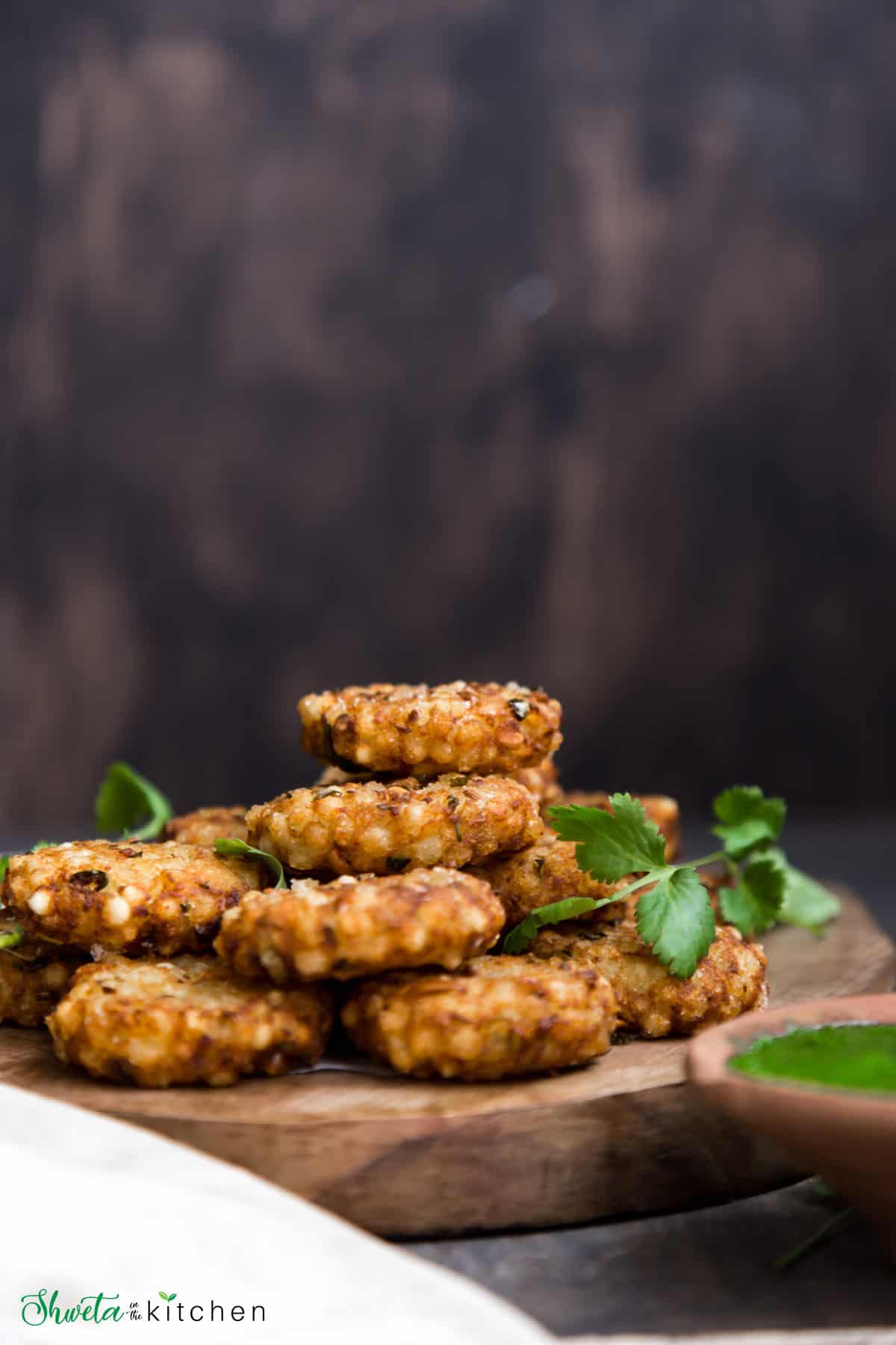 Sabudana vada stacked on top of each other on a serving board and garnished with cilantro