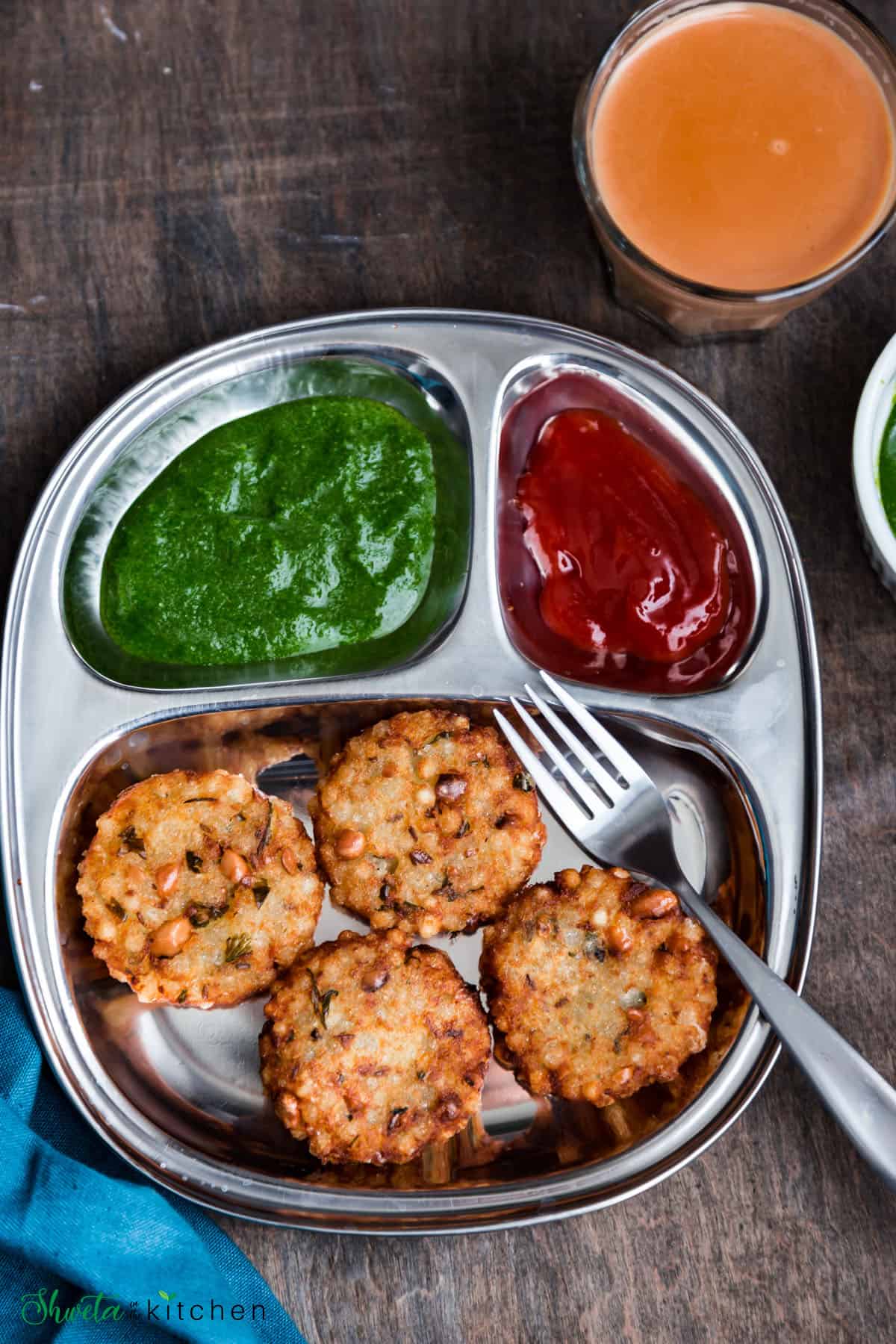 Sabudana Vada served in a silver tray with green chutney and ketchup