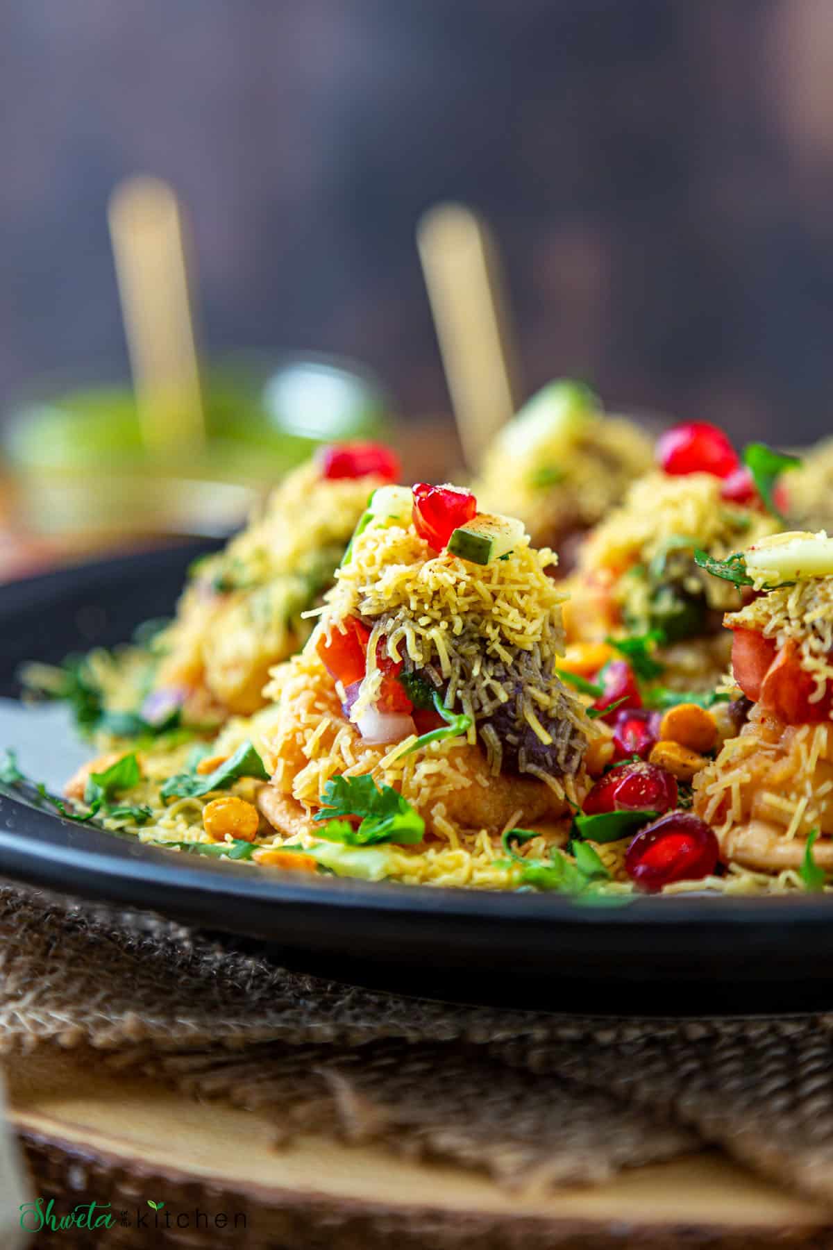 Close up side view of sev puri chaat on black plate