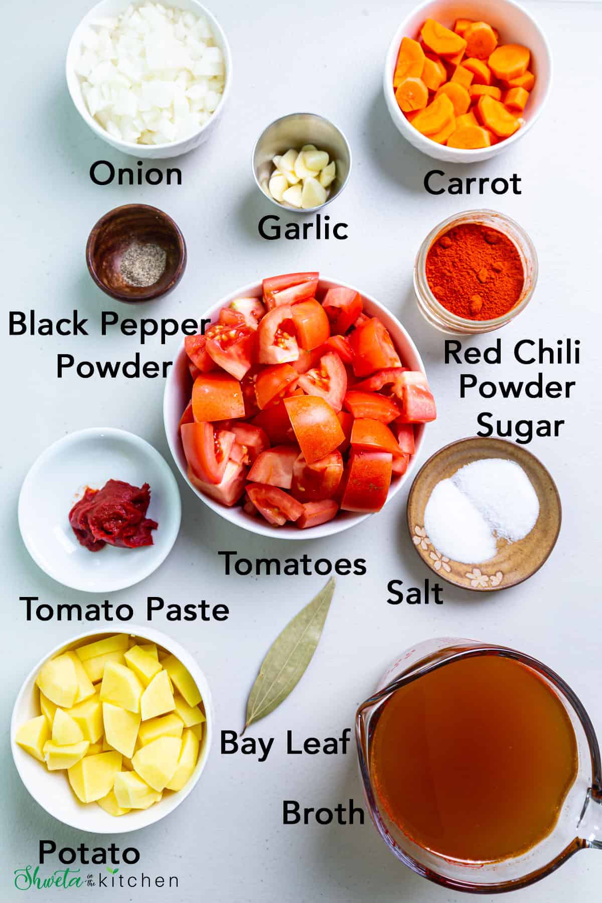 Ingredients for creamy vegan tomato soup in bowls on white surface