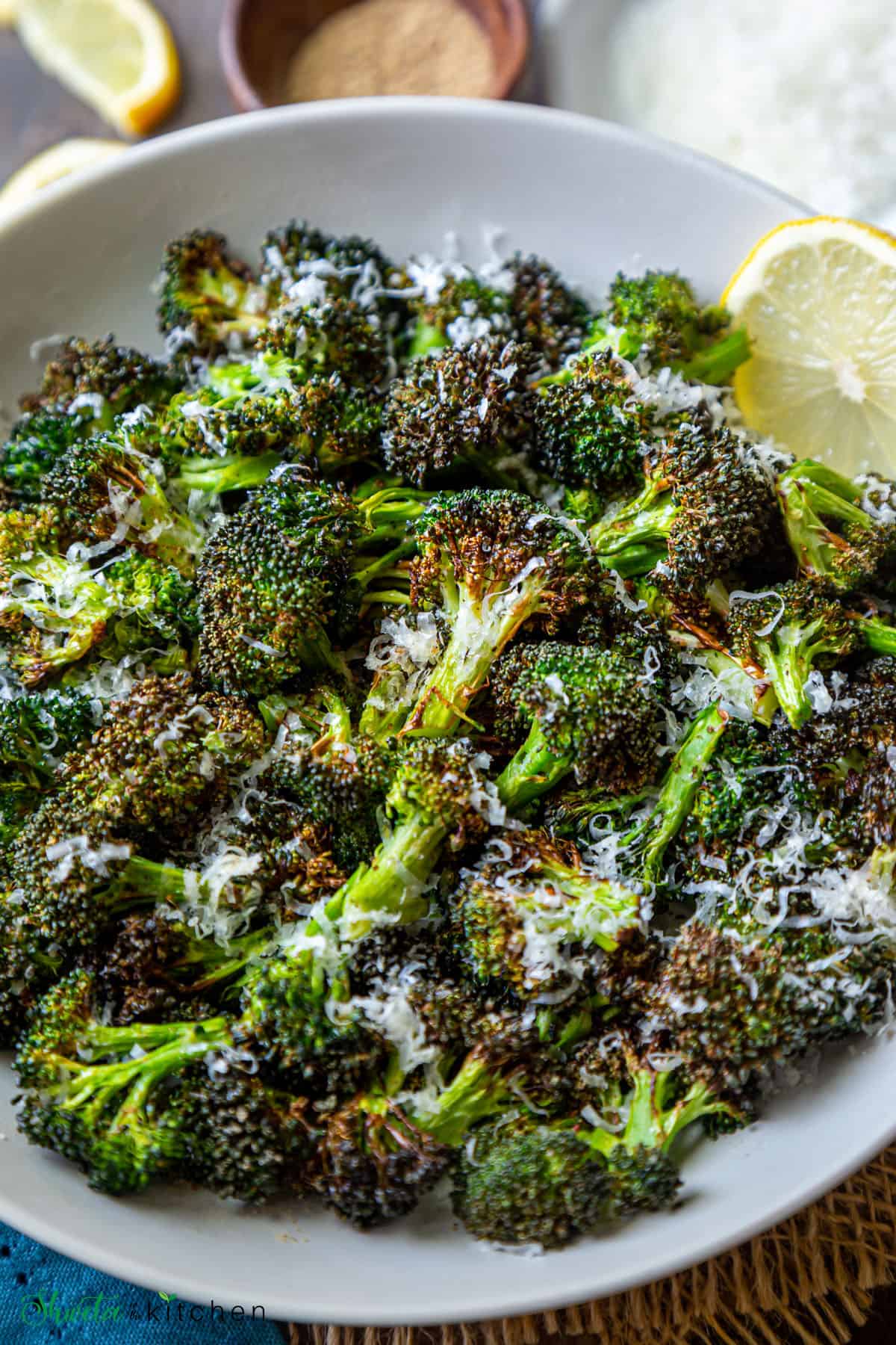 Air fried broccoli on a plate with lemon slice on side