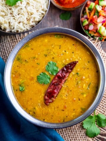 Dal Fry in a Round dish with rice, salad and pickle on side