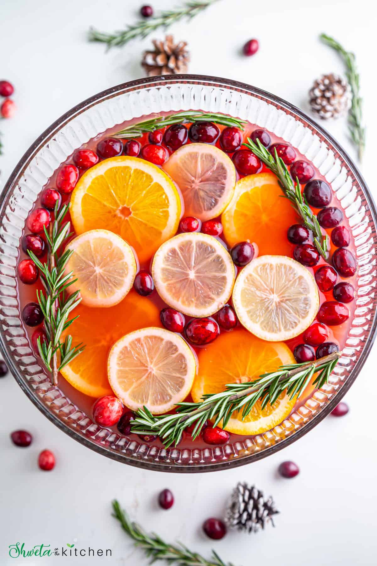 Top view of Christmas punch bowl garnished with cranberries, orange slice and rosemary