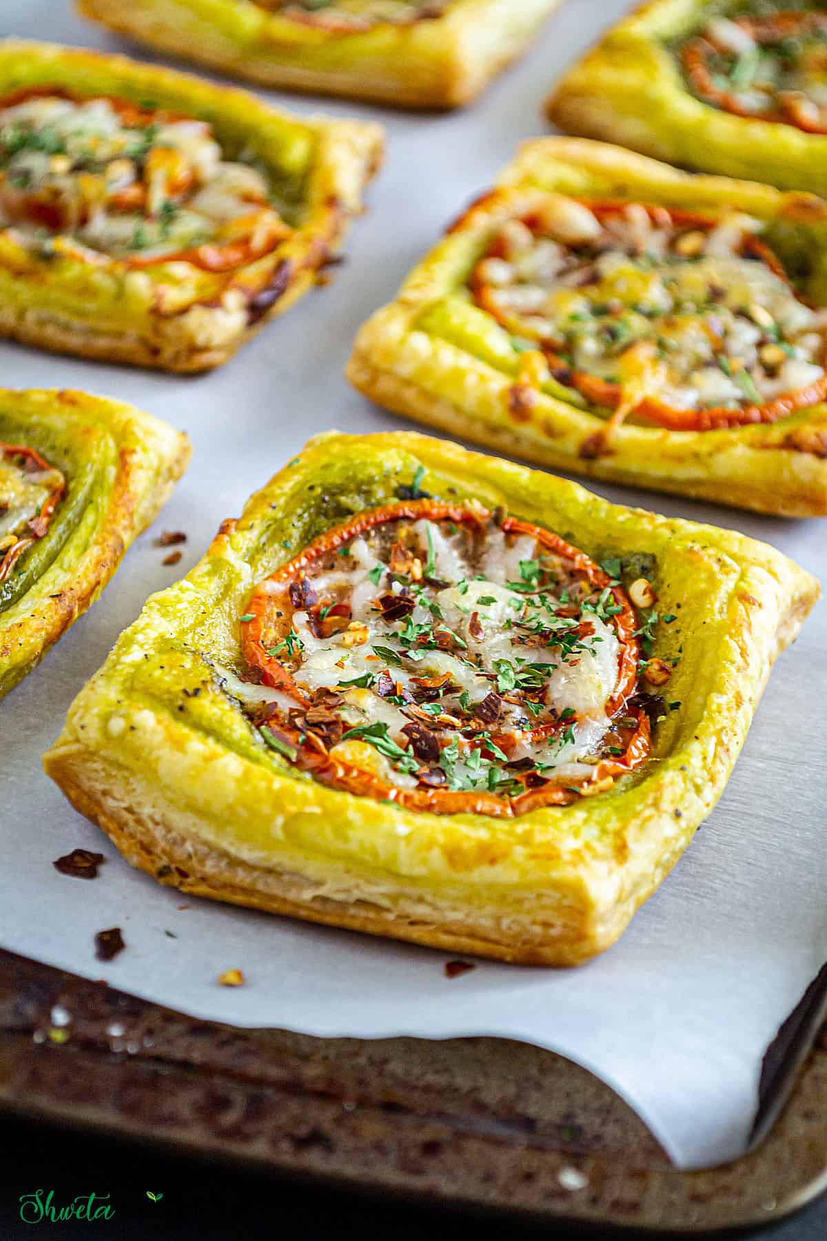 Tomato pesto tarts baked on a baking tray line with parchment