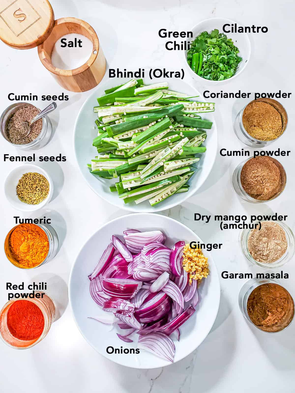 Ingredients for bhindi do pyaza arranged in bowls on white surface