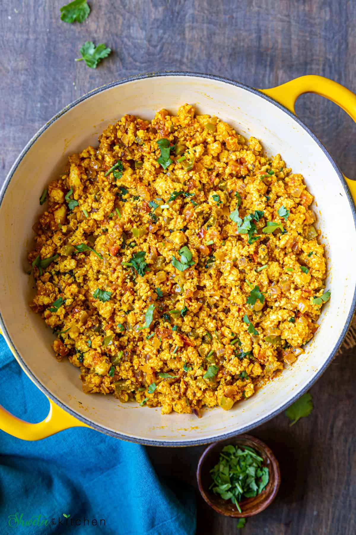 Dry Paneer bhurji served in a yellow wok garnished with fresh cilantro
