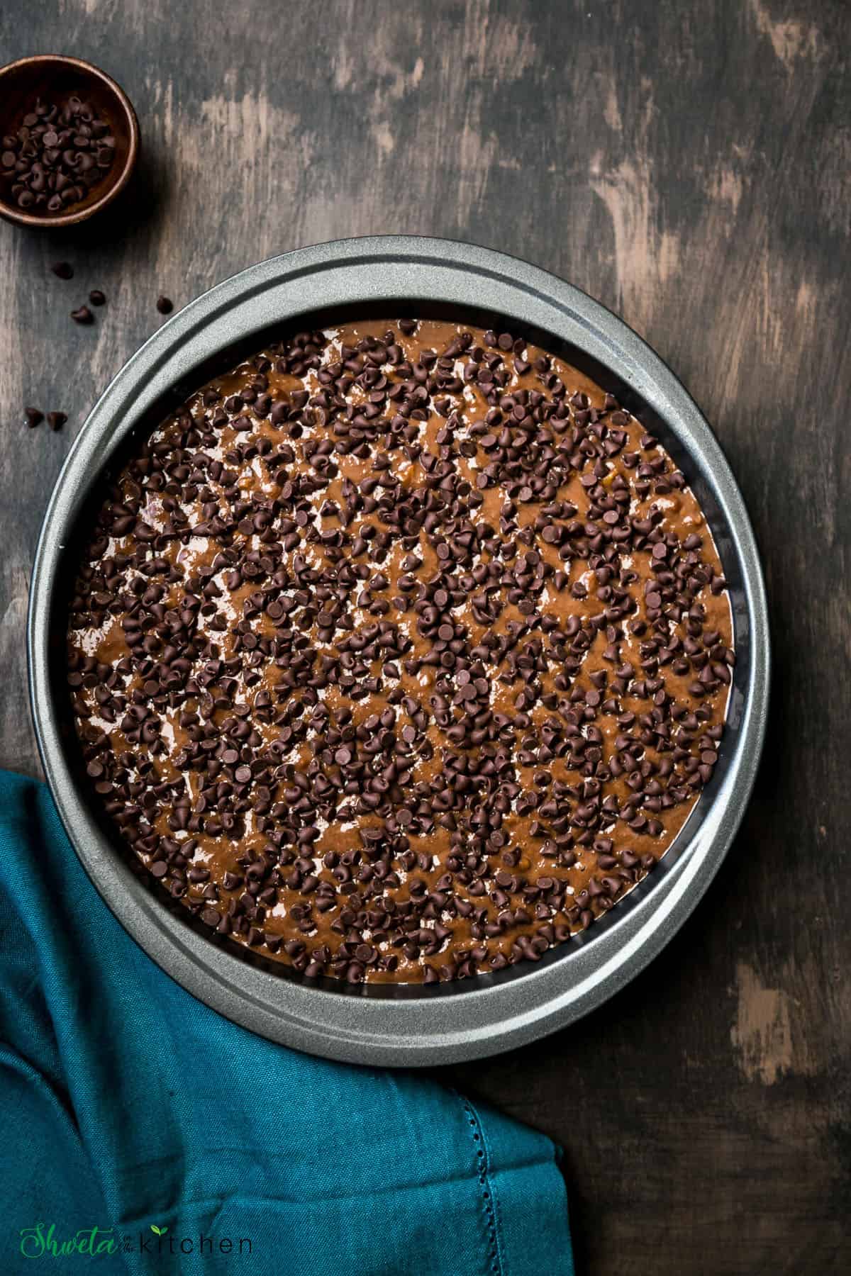 healthy chocolate banana cake batter in a cake pan topped with mini chocolate chips