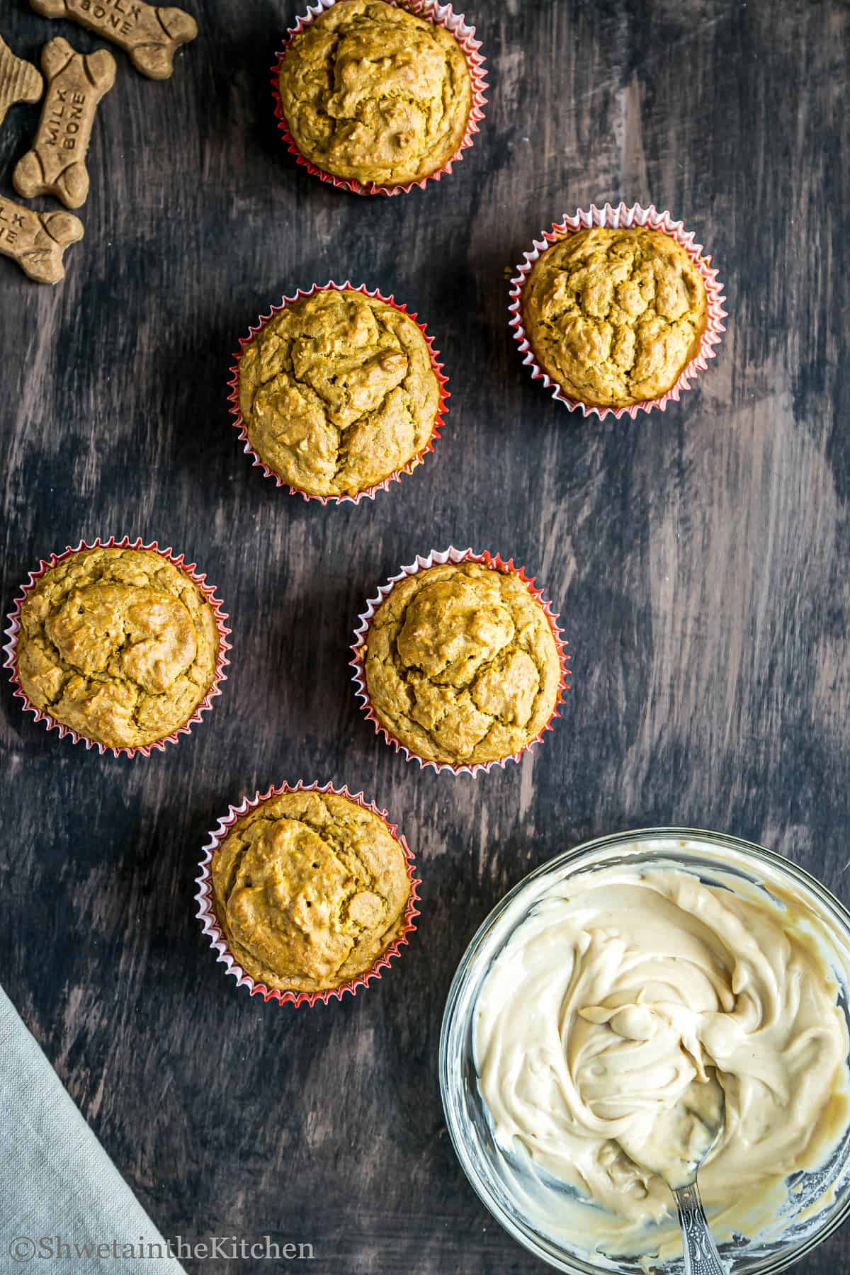 6 peanut butter pupcakes with bowl of peanut butter yogurt frosting on the side
