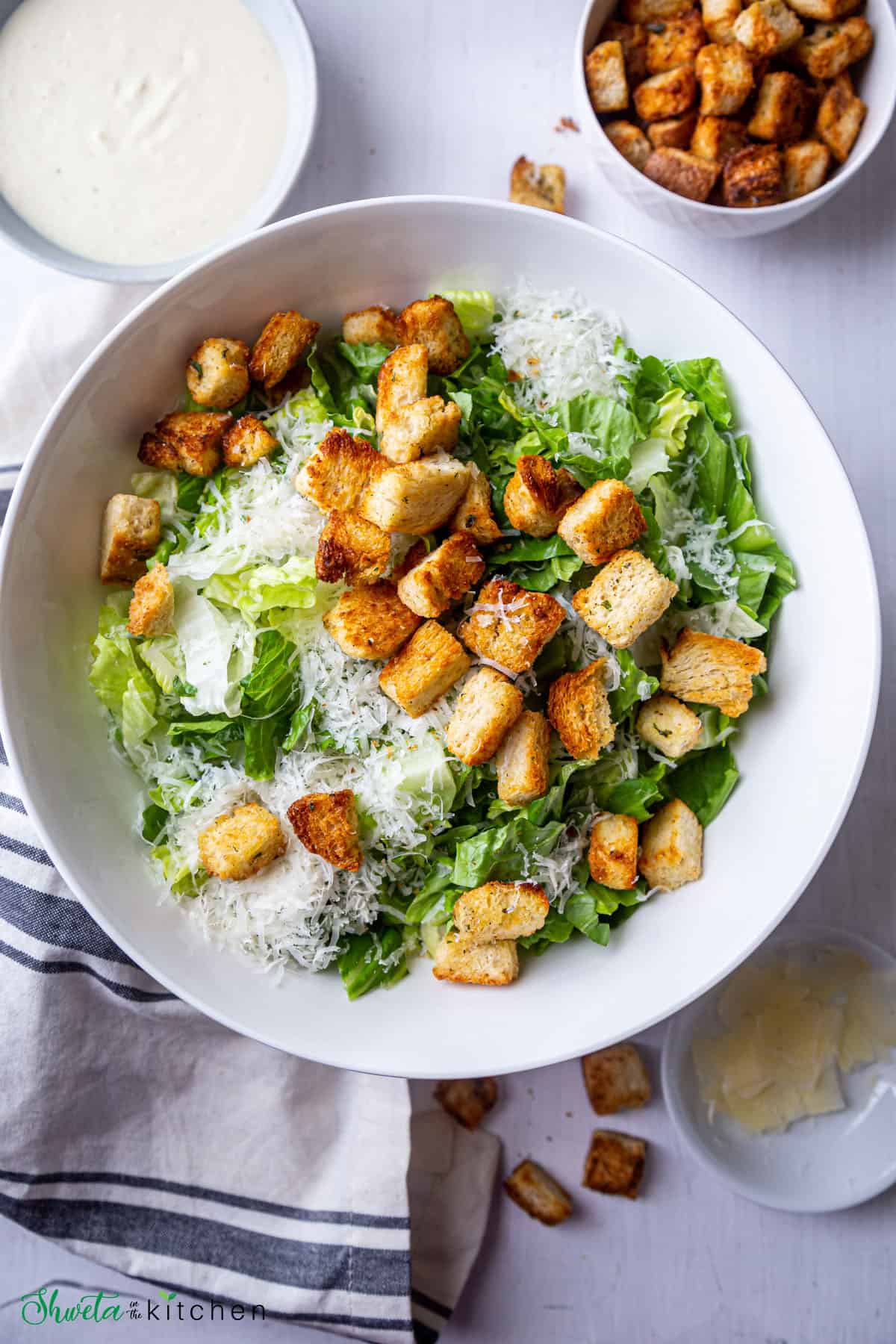 Bowl of eggless caesar salad with dressing and croutons on the side
