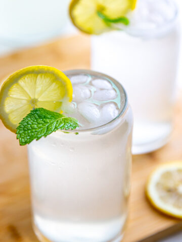 Two glass full of fresh squeezed lemonade garnished with lemon slice and mint leaves
