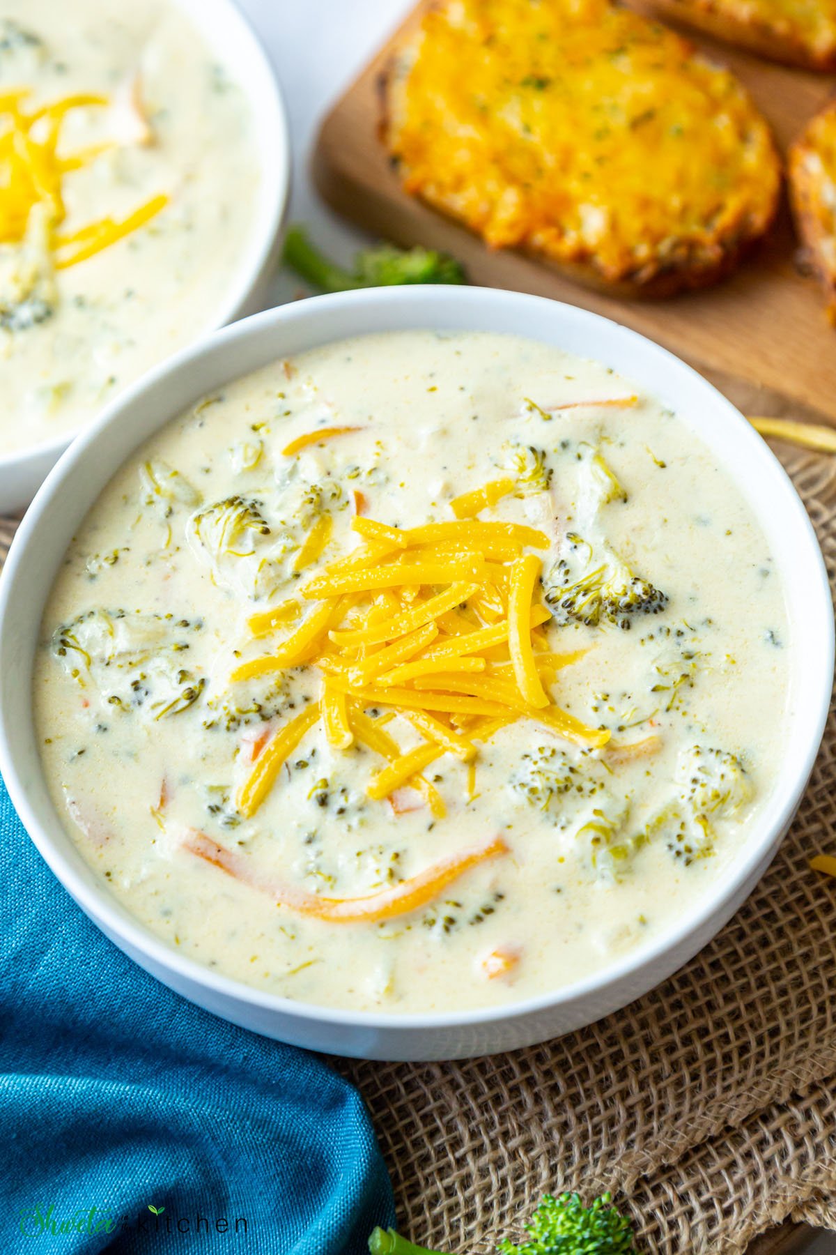 Side angled view of copycat panera broccoli cheddar soup in a bowl topped with cheese
