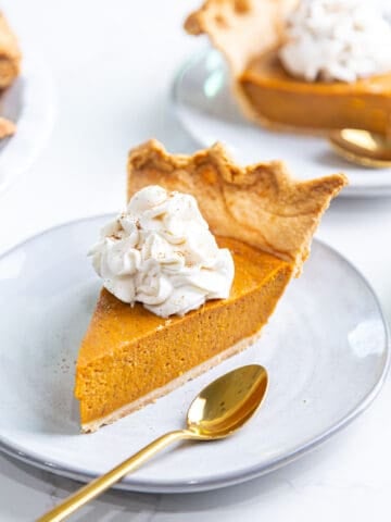 Slice of egg free pumpkin pie on a plate topped with whipped cream