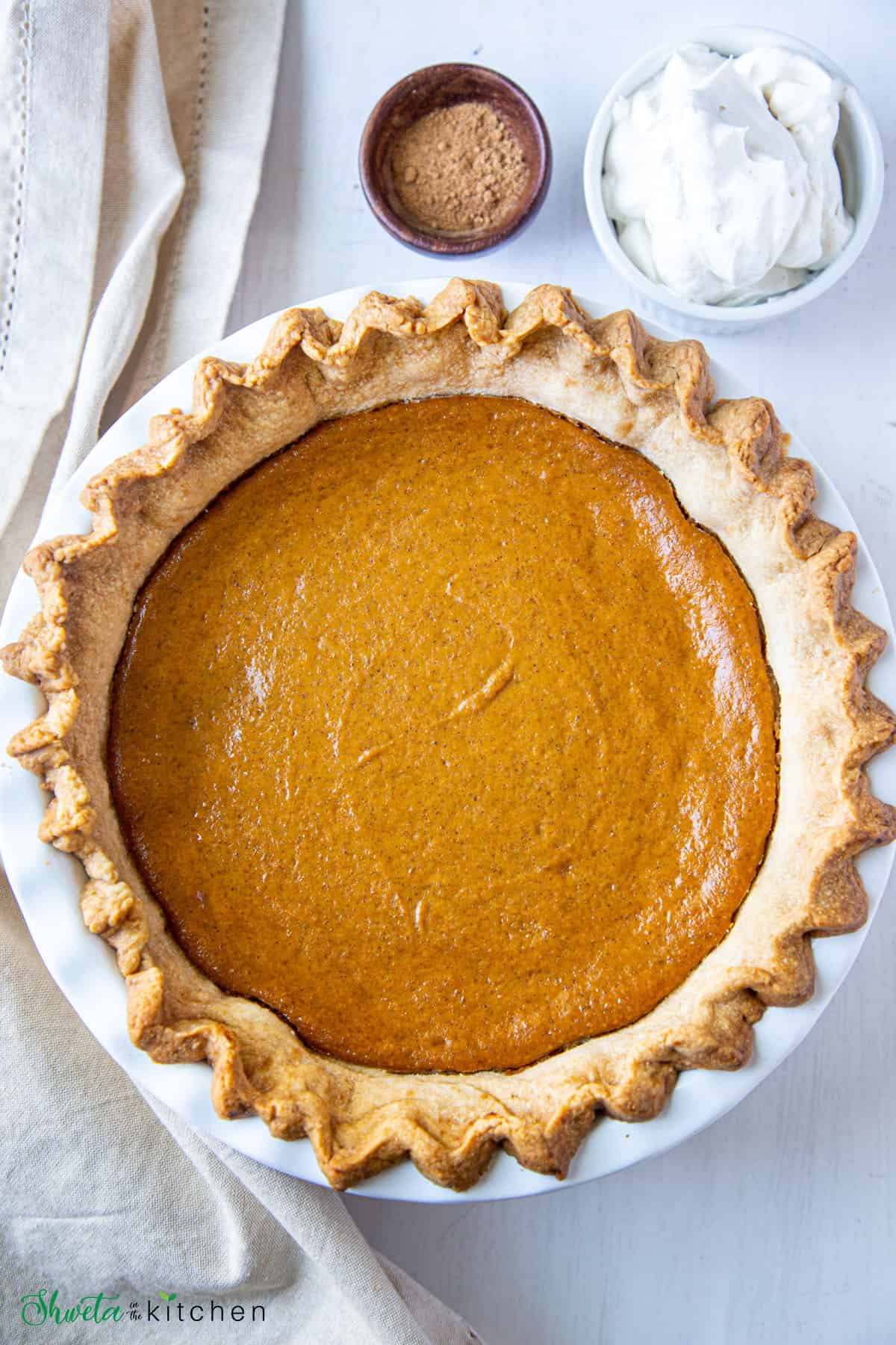 Baked eggless pumpkin pie with whipped cream on side 
