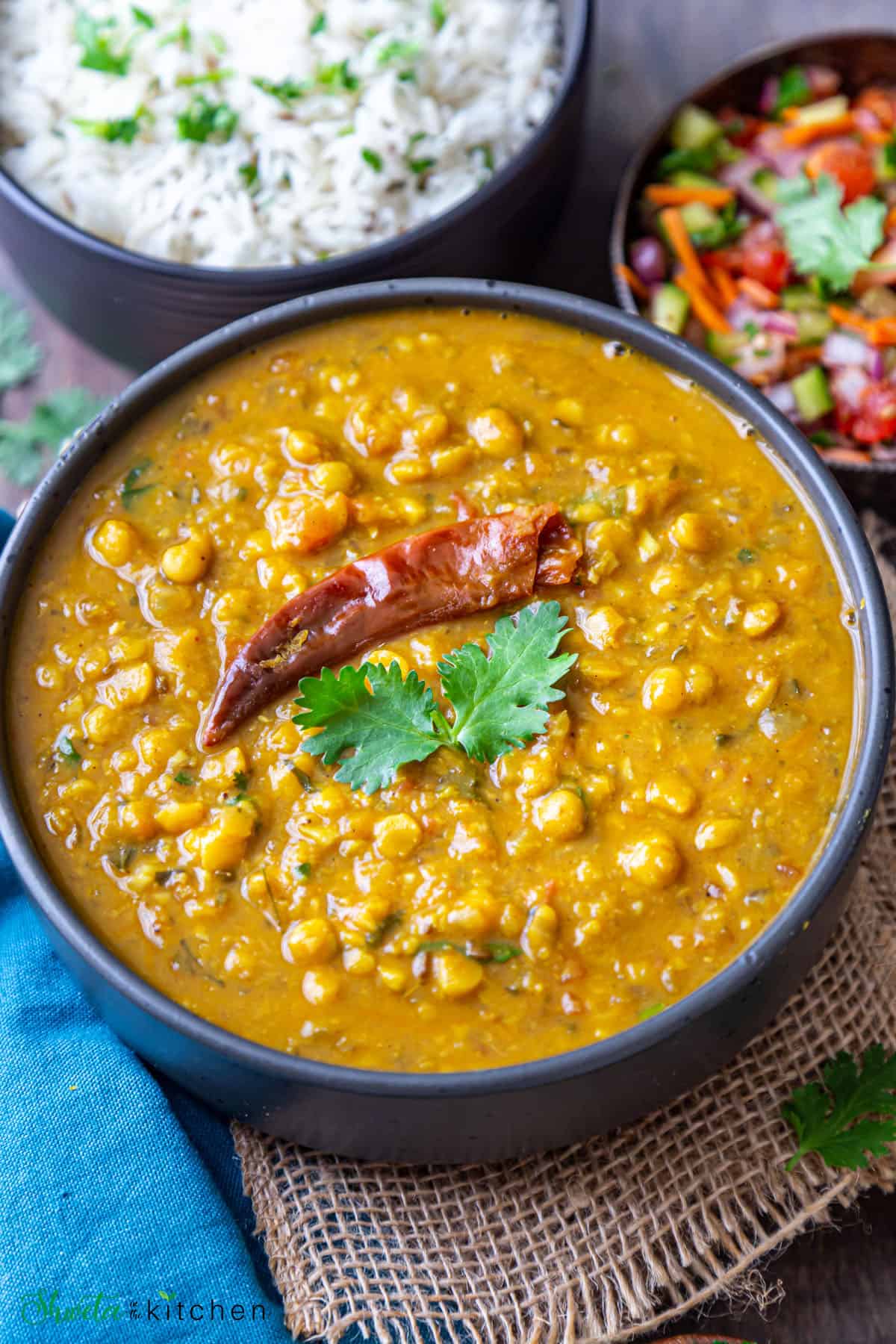 Sideview shot of chana dal served in a black bowl garnished with cilantro