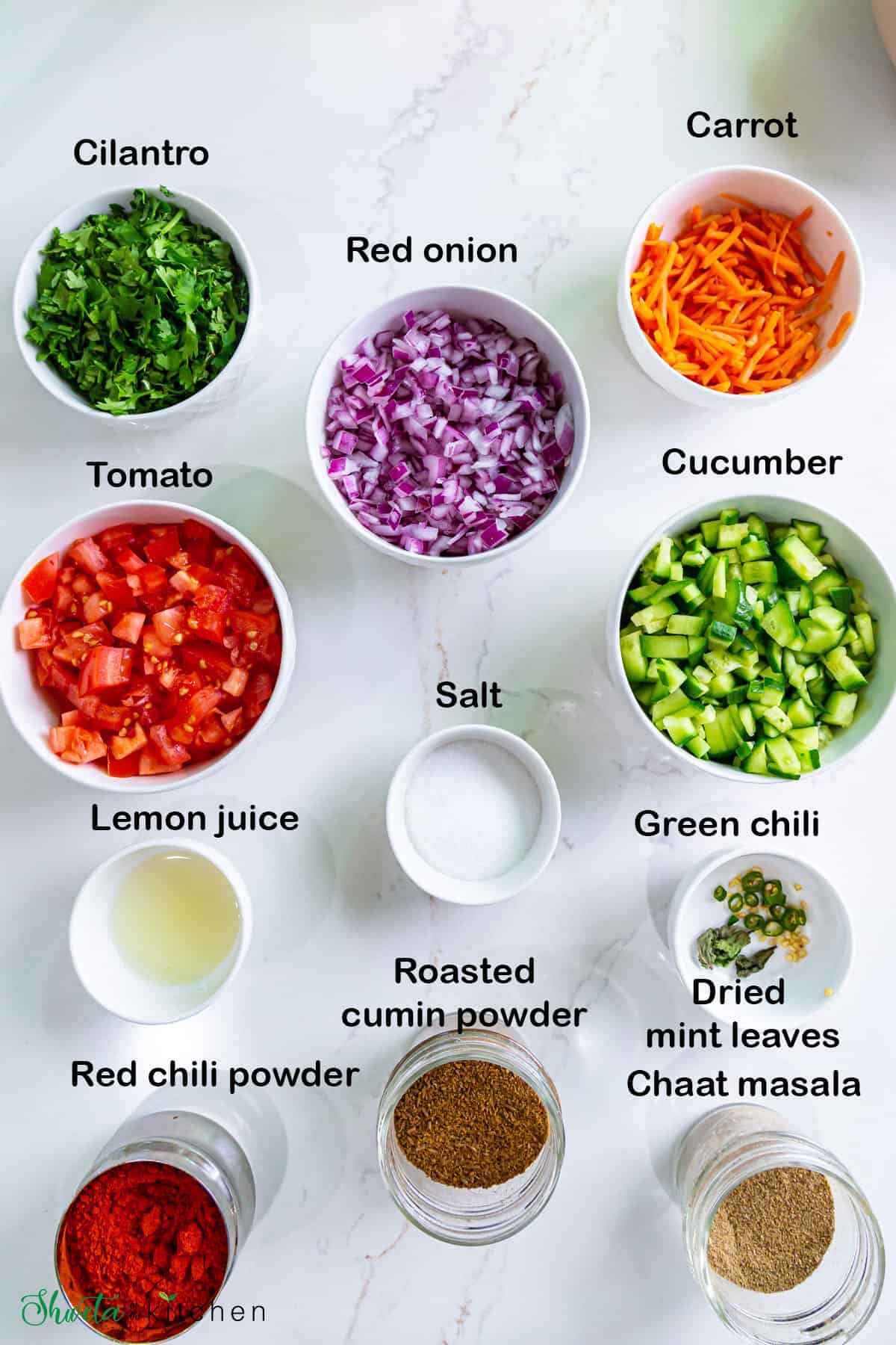 Ingredients for kachumber salad arranged in bowls on white surface