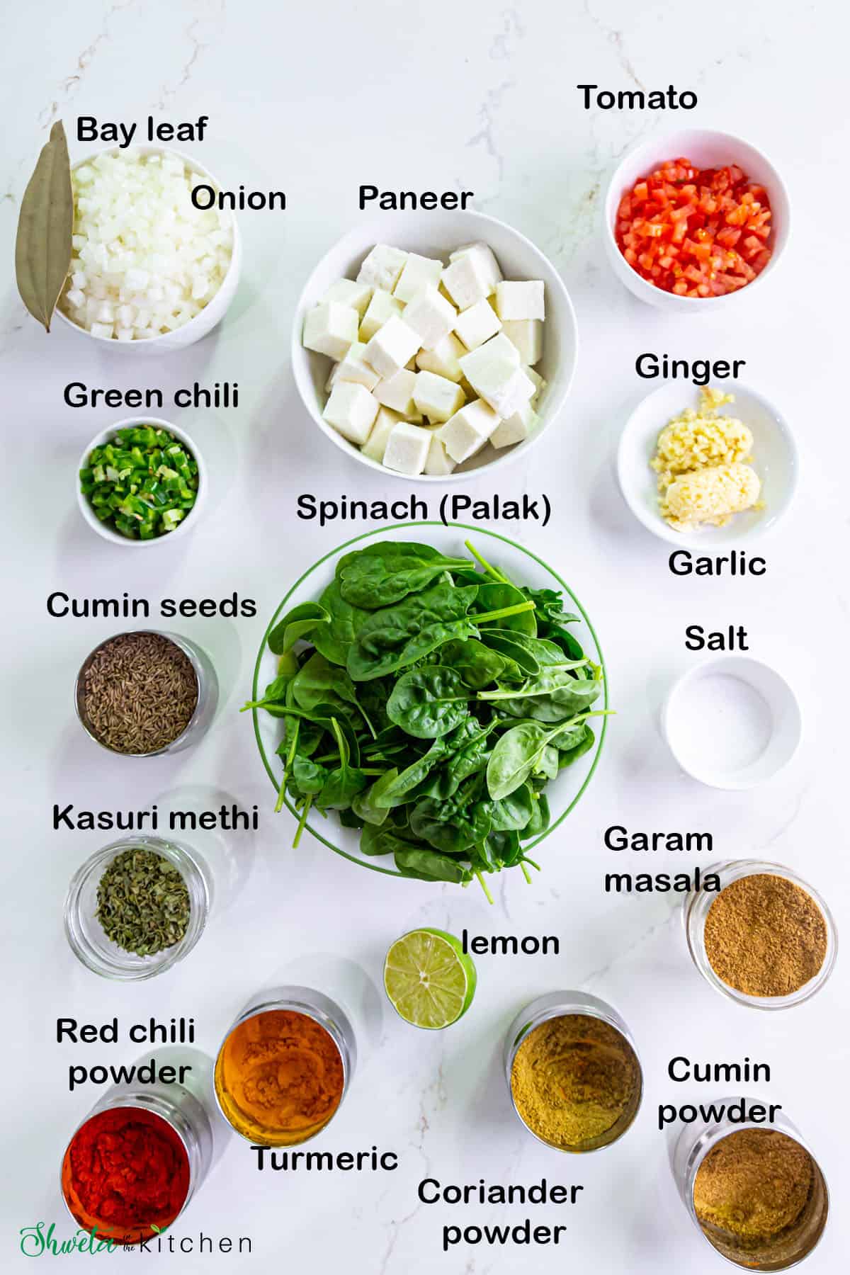 Ingredients for palak paneer arranged in bowls on white surface